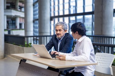 Asyalı son sınıf profesörü, üniversite fakültesi eğitim, akademik ve işletme fakültesinde otururken üniversite öğrencisine araştırma tezi hakkında tavsiyelerde bulunmaktadır.