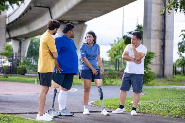 Bacağı kesilmiş insanlar, çeşitlilik toplumu, kapsayıcı modern altyapı ve erişilebilirlik tasarımı için arkadaşlarıyla birlikte parkta yürüyüş egzersizi yapıyorlar.