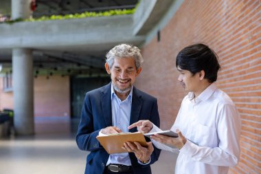 Asyalı son sınıf profesörü, üniversite fakültesi eğitim, akademik ve işletme fakültesinde otururken üniversite öğrencisine araştırma tezi hakkında tavsiyelerde bulunmaktadır.