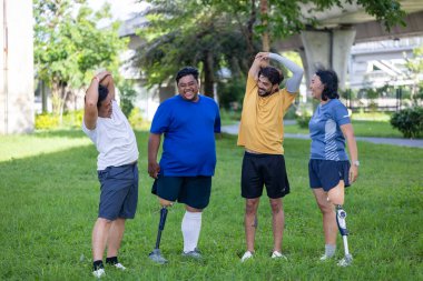 Kentsel halk parkında esneme egzersizinde bacağı kesilmiş insanların portresi ve arkadaşlarıyla birlikte kapsamlı modern altyapı ve erişilebilirlik tasarımı