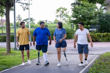Bacağı kesilmiş insanlar, çeşitlilik toplumu, kapsayıcı modern altyapı ve erişilebilirlik tasarımı için arkadaşlarıyla birlikte parkta yürüyüş egzersizi yapıyorlar.
