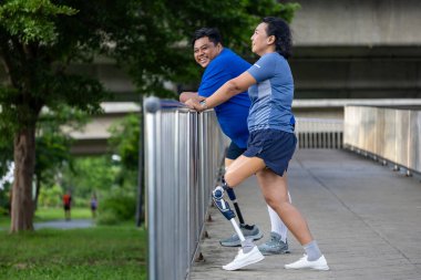 Bacağı kesilmiş Asyalı bir çift, çeşitlilik toplumu, kapsayıcı modern altyapı ve erişilebilirlik tasarımı için birlikte şehir yolunda yürüme egzersizi yapıyor.