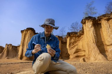 Asyalı jeolog, toprak ananın kavramını anlamak için bilimsel araştırma ve arkeoloji için doğal kumtaşı kanyonu taş ocağı kaynağındaki örnek kayayı araştırıyor ve inceliyor.