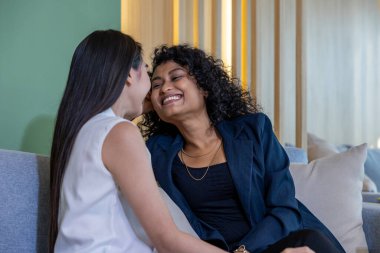 Farklı ırktan olan aynı cinsiyetten iki kadın, gurur ayında birlikte güzel vakit geçirirken aynı zamanda eşcinsellik ve ayrımcılığın eşitliği için kanepede oturuyorlar.