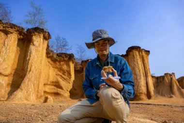 Asyalı jeolog, toprak ananın kavramını anlamak için bilimsel araştırma ve arkeoloji için doğal kumtaşı kanyonu taş ocağı kaynağındaki örnek kayayı araştırıyor ve inceliyor.