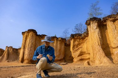 Asyalı jeolog, toprak ananın kavramını anlamak için bilimsel araştırma ve arkeoloji için doğal kumtaşı kanyonu taş ocağı kaynağındaki örnek kayayı araştırıyor ve inceliyor.