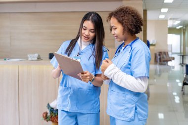 Çeşitlilik doktoru ve hemşire, deneyimli bir hekim uzmanıyla, tam bakım planı üzerine, hastanın tıbbi kayıtlarını tartışıyor ve beyin fırtınası yapıyor.