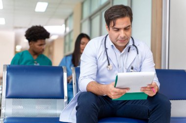 Doktor, hastanenin yoğun bakım servisinin yanındaki sağlık ve hemşirelik bölümünde çalışırken gelecekteki bakım planı için hastanın tıbbi kayıtlarını ve akış çizelgesini okuyor.