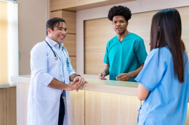 Çeşitlilik doktoru ve hemşire, deneyimli kıdemli hekim uzman doktorla, tam bakım planı üzerine, hastanın tıbbi kayıtlarını tartışıyor ve beyin fırtınası yapıyor.