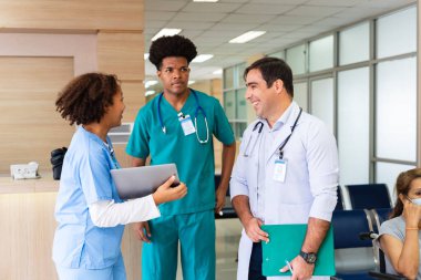 Çeşitlilik doktoru ve hemşire, deneyimli kıdemli hekim uzman doktorla, tam bakım planı üzerine, hastanın tıbbi kayıtlarını tartışıyor ve beyin fırtınası yapıyor.