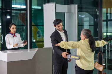 Havaalanı personeli güvenlik için metal tarayıcı kullanıyor. Uçağa binmeden önce havaalanındaki tüm yolcuları güvenlik protokolü için kontrol edin.