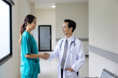 Asyalı doktor ve hemşire ekibi deneyimli uzman hekim konseptiyle tam bakım planı için hastanın tıbbi kayıtları üzerinde çalıştıktan sonra el sıkışıyorlar.
