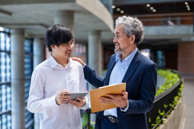 Asyalı son sınıf profesörü, üniversite fakültesi eğitim, akademik ve iş alanında otururken üniversite öğrencisine araştırma tezi hakkında danışmanlık yapıyor.