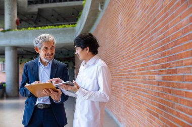 Asyalı son sınıf profesörü, üniversite fakültesi eğitim, akademik ve iş alanında otururken üniversite öğrencisine araştırma tezi hakkında danışmanlık yapıyor.