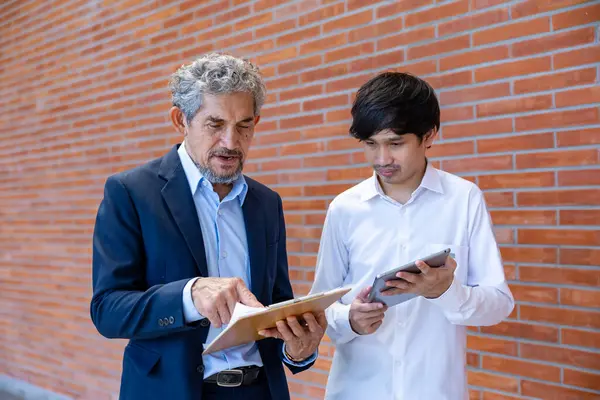 Asyalı son sınıf profesörü, üniversite fakültesi eğitim, akademik ve iş alanında otururken üniversite öğrencisine araştırma tezi hakkında danışmanlık yapıyor.