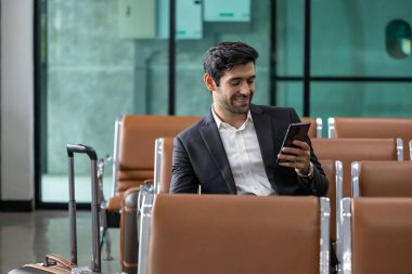 Kafkasyalı işadamı havayolu şirketinin kalkış salonunda uçağa binmeyi beklerken akıllı cep telefonu kullanıyor.