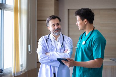 Kıdemli doktor, deneyimli hekim konseptiyle ilgili kesin bakım planı için genç hemşireyle hasta kaydı üzerine beyin fırtınası yapıyor.