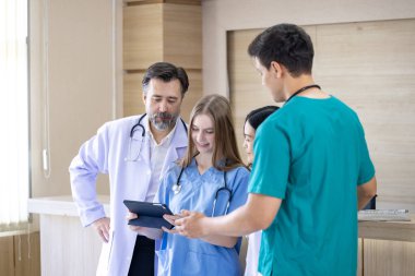 Çeşitlilik doktoru ve hemşire, deneyimli kıdemli hekim uzman doktorla, tam bakım planı üzerine, hastanın tıbbi kayıtlarını tartışıyor ve beyin fırtınası yapıyor.