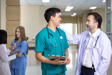 Kıdemli doktor, deneyimli hekim konseptiyle ilgili kesin bakım planı için genç hemşireyle hasta kaydı üzerine beyin fırtınası yapıyor.