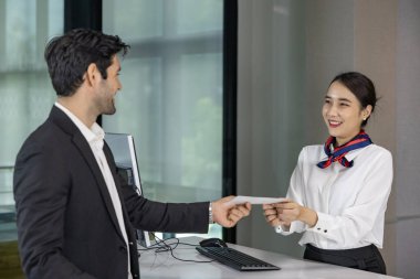 Kafkas işadamı yolcu, uçağa binmeden önce son bir teftiş için kalkış terminalinde kontrol masasında bulunan havayolu zemin mürettebatından biniş kartı alıyor.