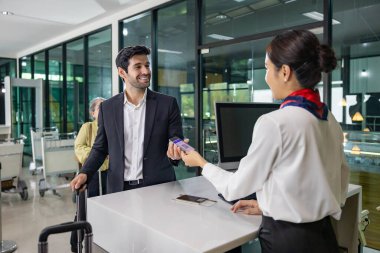 Kafkas işadamı yolcu, uçağa binmeden önce son bir teftiş için kalkış terminalinde kontrol masasında bulunan havayolu zemin mürettebatından biniş kartı alıyor.