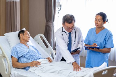 Asyalı doktor, uzun süreli sigara içme hastalığı ve tedavi programı kullanımı nedeniyle hastanede akciğer kanserinden muzdarip olan yaşlı bir hastaya tedavi planını anlatıyor.