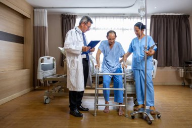 Doktor ve hemşire, Walker 'ı rehabilitasyon ve fizik tedavi ve iyileşme süreci için ameliyat sonrası yürüme egzersizinde kullanması için destekliyor.