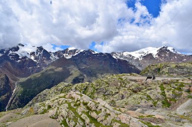 Dağ manzarası, karla kaplı tepeler ve bulutlar.