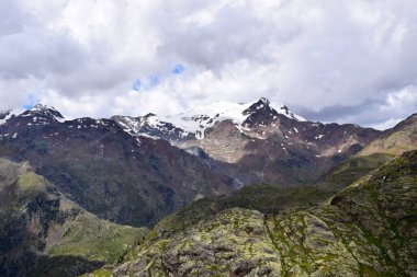 Güzel yüksek dağ manzarası, karlı ve bulutlu zirveler.