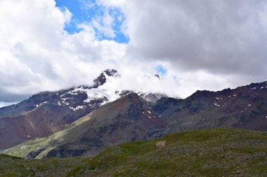 Bulutlu ve yüksek karlı zirveli gizemli dağ manzarası