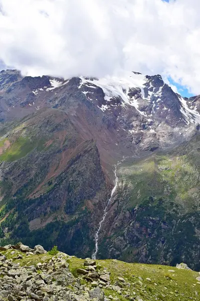 Dağ manzarası, yüksek dağlar, karla kaplı tepeler ve bulutlar.