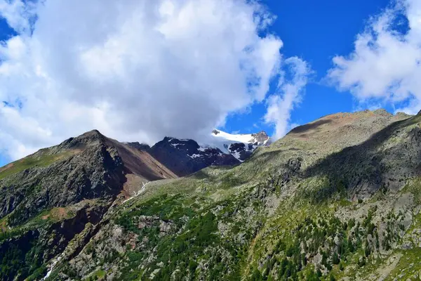 Dağ manzarası, karlı tepeler bulutların arkasında saklı.