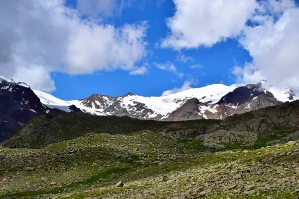 Bulutlar ve yüksek karlı platoyla inanılmaz bir dağ manzarası.