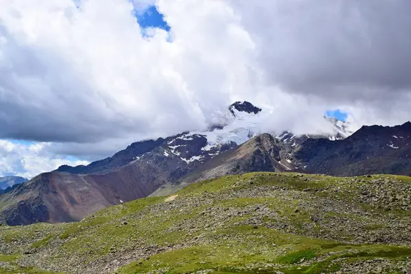 Bulutları ve yüksek karlı zirvesi olan güzel bir dağ manzarası