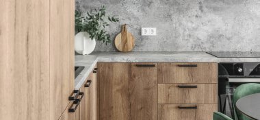 Modern minimalist mutfak ve yemek odası içi ahşap ve beyaz yüzeyler, yeşil sandalyeler ve seramik vazoda okaliptüs. Estetik basit iç tasarım konsepti.