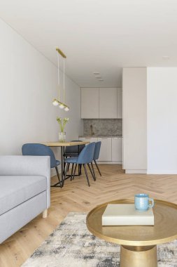 Modern minimalist kitchen and dining room interior design  with wooden furniture, oak floor. blue chairs.  Aesthetic simple interior design concept.