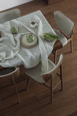 Seramik yemek takımı, keten masa örtüsü, yemek sandalyeleri, enginar ve kuşkonmazlı basit bir yemek masası organizasyonu. Ev dekorasyonu kavramı