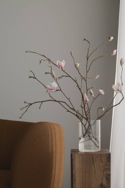 Temiz cam vazodaki bir manolya dalı Japonya 'nın iç kısımlarındaki bir meşe ağacının gövdesine dayanır. Yumuşak çiçekler ve ılık odun huzurlu, minimalist bir atmosfer yaratır..