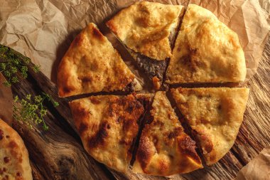 Geleneksel bir Khachapuri, kırsal ahşap arka planda güneşli bir ışıkta güneşleniyor, altın kabuğunu ve yapışkan peynirini vurguluyor..