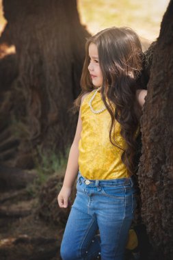 Ağaçta poz veren sarışın bir kız. Mutluluğun ifadesi. Manken kız. çocuk günü teması.