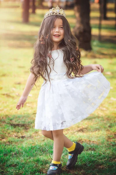 Little girl in white dress and princess crown, she poses for the camera with a beautiful look, copy space, children\'s day theme.