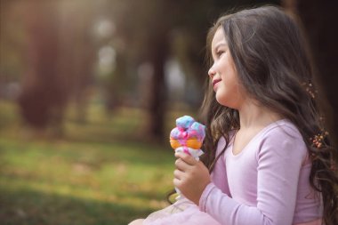 Güzel bir yaz gününde ormanda dondurma yiyen tatlı, kıvırcık saçlı kız, çocuk günü konsepti, sıcak bir günün keyfini çıkaran mutlu kız..