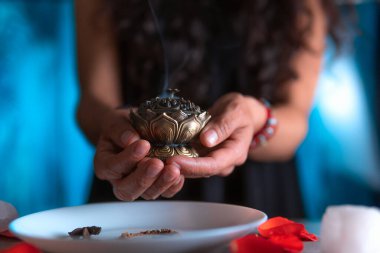 Tütsü yakan ellerin yakın çekimi, ölüler gününde cadı temizleme ritüeli yapıyor, Cadılar Bayramı, ruhani inanışlar, beyaz büyü.