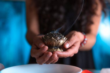 Tütsü yakan ellerin yakın çekimi, ölüler gününde cadı temizleme ritüeli yapıyor, Cadılar Bayramı, ruhani inanışlar, beyaz büyü.