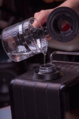 Kadın Barista lezzetli bir kahve hazırlamak için makineyi çalıştırıyor, yakın plan kahve hazırlıyor, kahve hazırlamak için su dolduruyor..