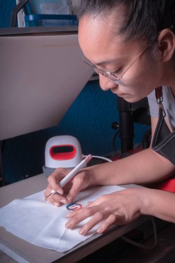 Genç kadın fazla malzemeyi yabani otlarla, işyerini kesme aletleriyle, aletlerle, seçici odak noktalarıyla temizler.