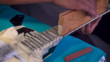 Luthier 'in elektro gitar tamiratı, fret öğütme, fretboard zımparalama ve cilalama, müzik aleti atölyesi, gitar tamir eden ellerin yakın çekimi..