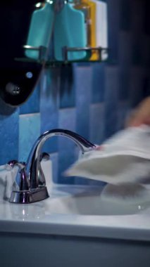 Lavaboyu temizlemek, lavaboyu kuru havluyla silen adamın dikey görüntüsü, banyo temizliği.