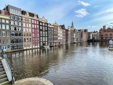 Amsterdam 'daki Damrak Kanalı' nda tekne turları için tekneleri olan eski geleneksel Hollanda mimari binaları.