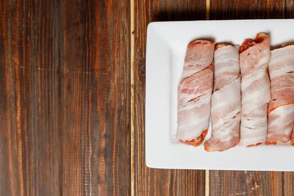 コックは肉を炒める準備をしている 白いプレートの中に肉のロールがたくさんあります 調理されると肉は驚くほどになります 美味しくておいしいですよ 食物は木のテーブルの上にある — ストック写真